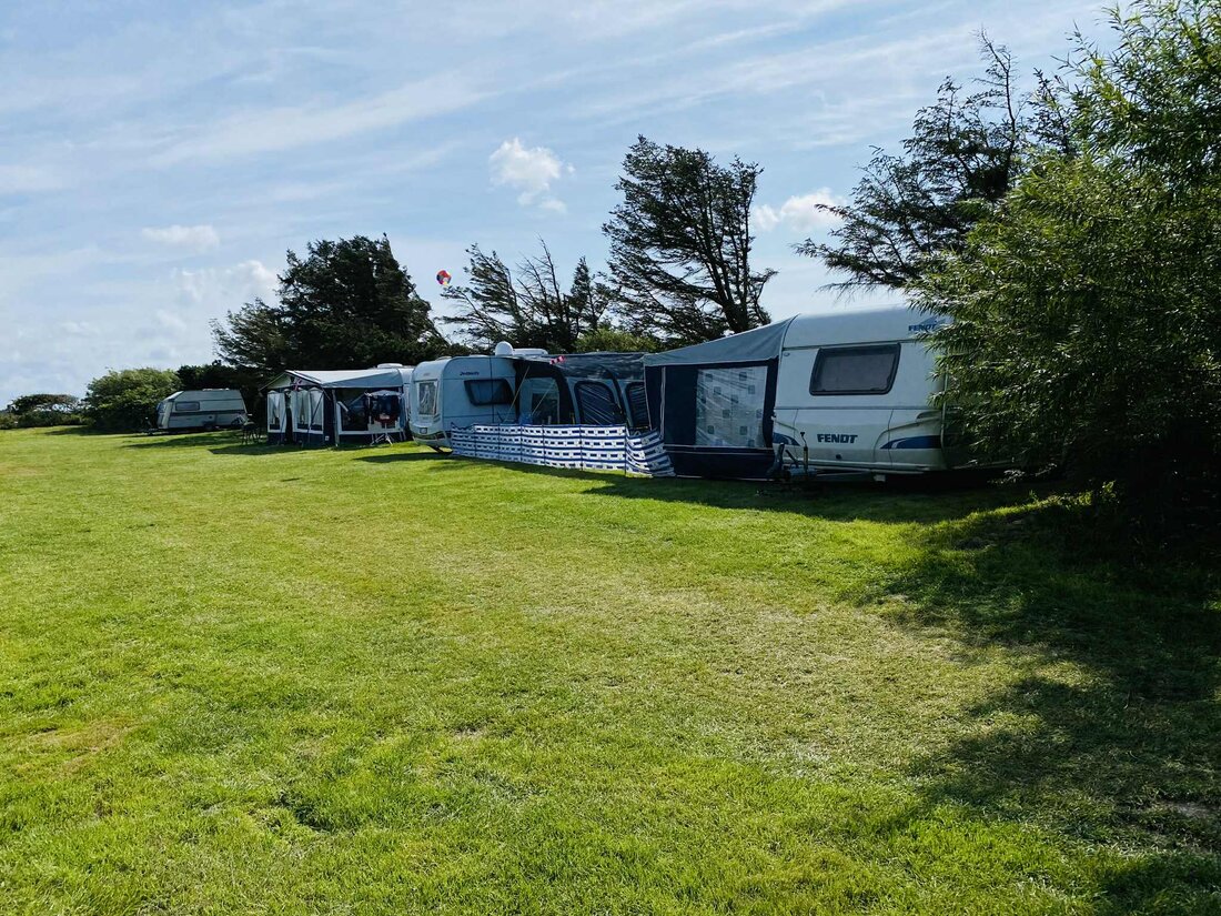 Caravans and tents on grassy pitches near dunes